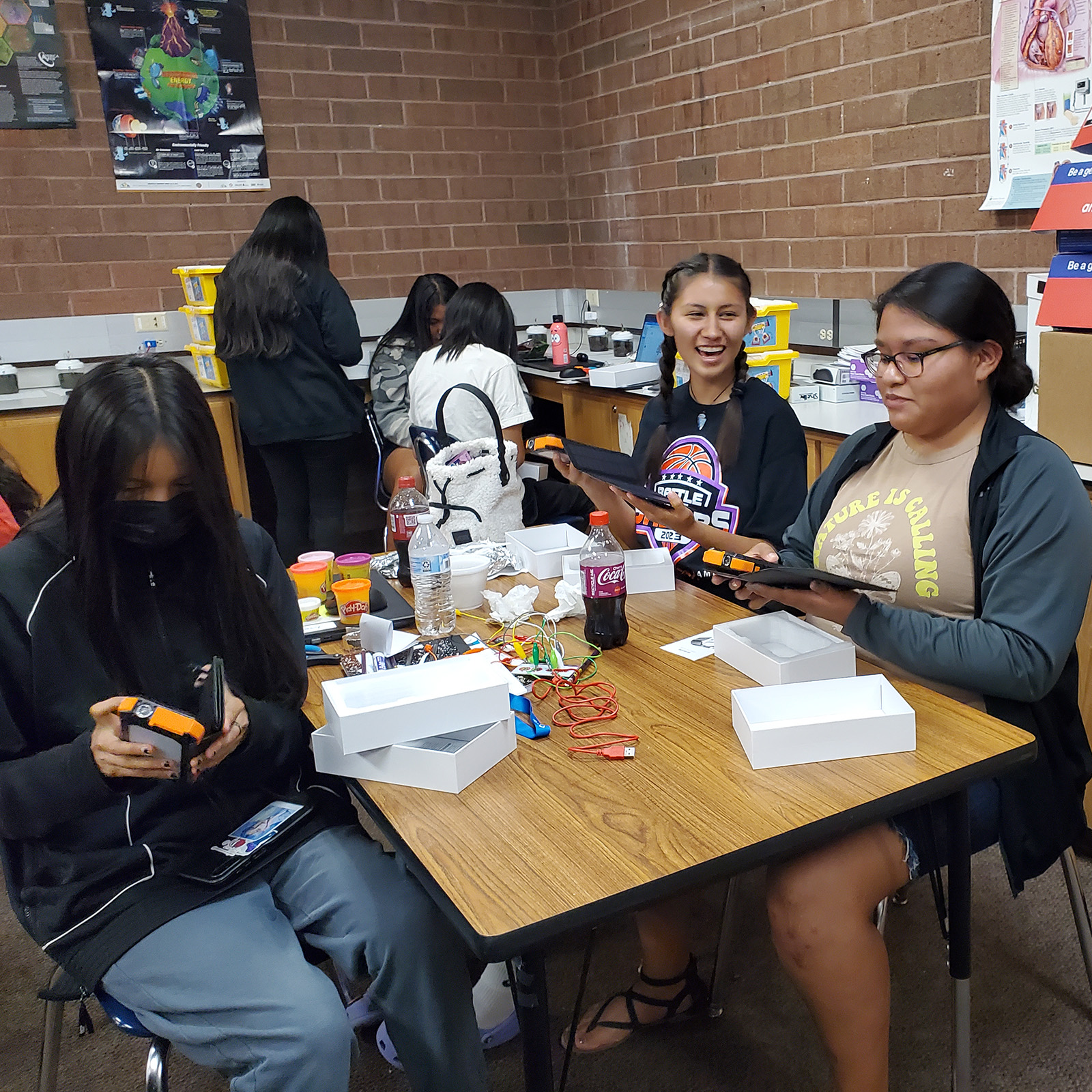 two groups of students exploring solar powered phone battery banks.